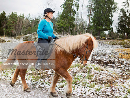 Senior woman riding on Icelandic horse