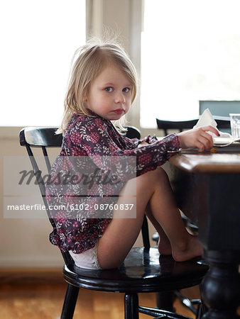 Girl sitting at kitchen table and looking at camera