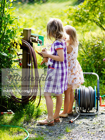 Girls washing carrots at pump
