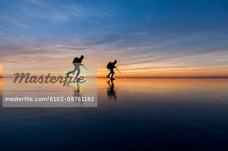 People long-distance skating at sunset, Vanern, Sweden