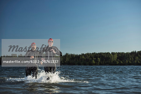 Woman in wetsuit running in sea, Sweden