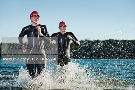 Woman in wetsuit running in sea, Sweden