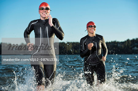 Woman in wetsuit running in sea, Sweden