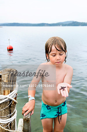 Boy on jetty holding starfish