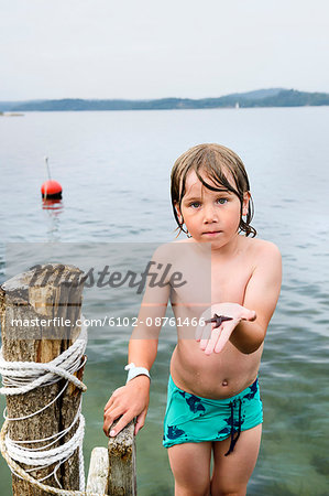 Boy on jetty holding starfish