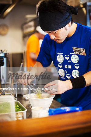 The ramen noodle shop. A man preparing a ramen noodle dish from selected ingredients.