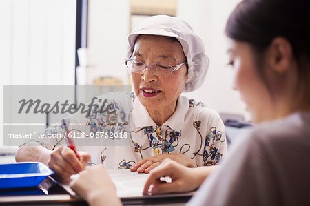 A mature woman at a desk in the office of a fast food unit and noodle production factory.