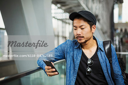 A man in a blue jacket in a modern building using his smart phone.