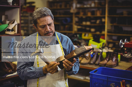 Shoemaker hammering on a shoe in workshop