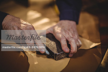 Shoemaker cutting a piece of leather in workshop