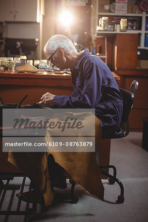 Shoemaker applying glue on shoe in workshop