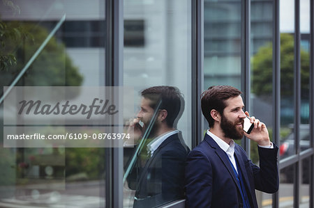 Businessman talking on mobile phone outside office