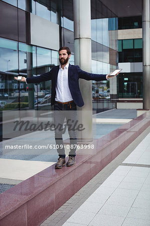 Businessman holding mobile phone and digital tablet while walking on passage