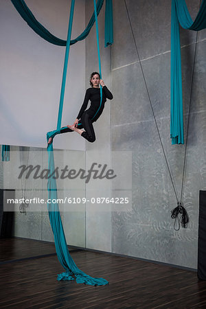 Gymnast exercising on blue fabric rope in fitness studio