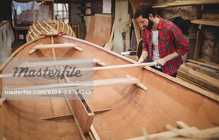 Man preparing wooden boat frame in boatyard