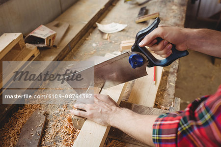 Man cutting a wooden plank at boatyard