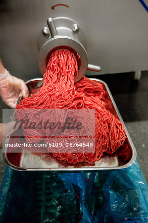 Minced meat coming out from grinder at butchers shop