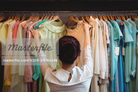 Woman selecting a clothes from hanger at boutique store