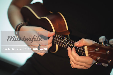 Mid-section of woman playing a guitar in music school