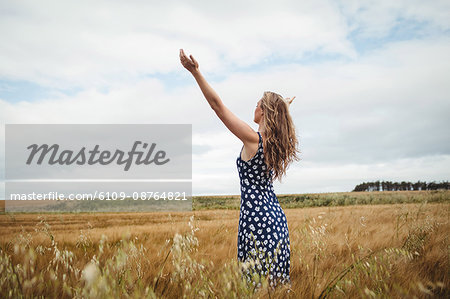 Rear view woman standing with arms outstretched in field