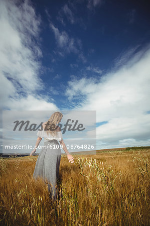 Rear view of woman touching wheat in field