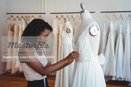 Female fashion designer adjusting the dress on a mannequin in the studio