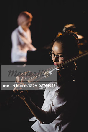 Female student playing violin in a studio