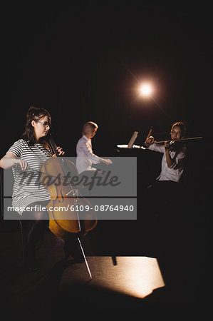Three female students playing double bass, violin and piano in a studio