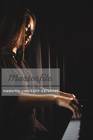 Female student playing piano in a studio