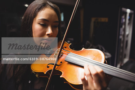 Female student playing violin in a studio