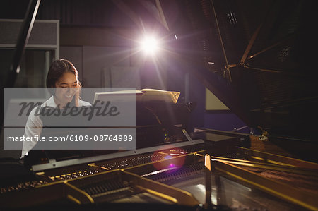 Female student playing piano in a studio