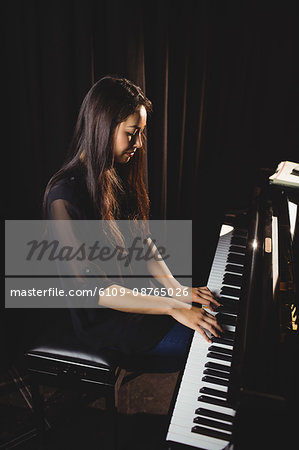Beautiful woman playing a piano in music studio