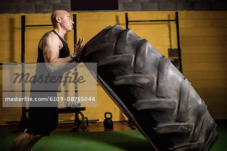 Thai boxer lifting heavy tyre in the fitness studio