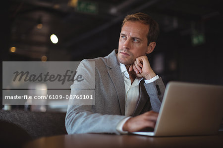 Thoughtful Business man using laptop at desk in office