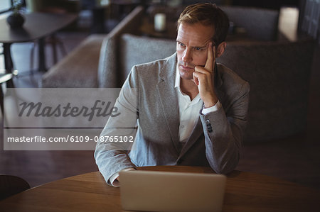 Thoughtful Business man using laptop at desk in office