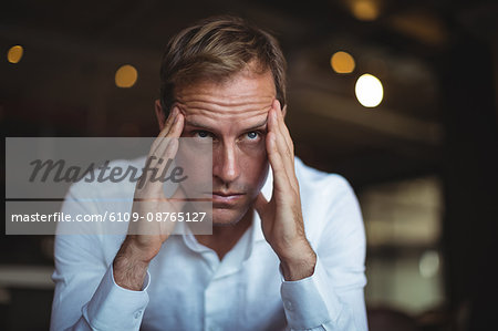 Close-up of tensed businessman sitting with hand on temple