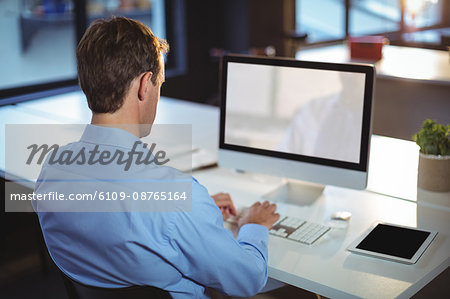 Rear view of businessman using desktop pc at office