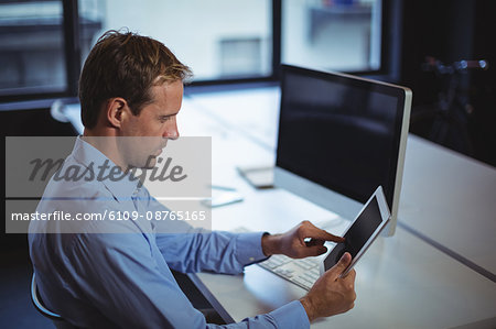 Businessman using digital tablet and desktop pc in office