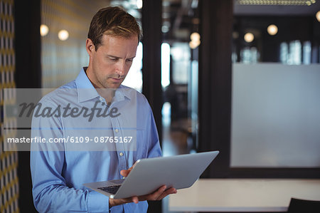 Thoughtful businessman using laptop in office