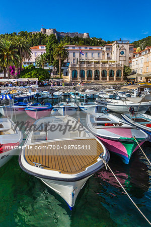 Boats docked at marina with the Venetian Loggia and the Hvar Fortress overlooking the harbour at the Old Town of Hvar on Hvar Island, Croatia