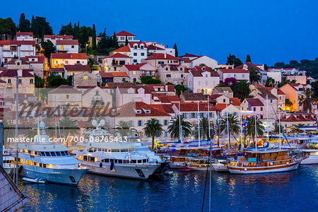 Marina with yachts and classic sailing ships in front of the Old Town of Hvar at dusk on Hvar Island, Croatia