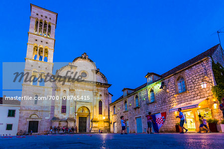 Children playing in St Stephen's Square at night holding Croatian national flag at dusk with Cathedral of St Stephen in Old Town of Hvar on Hvar Island, Croatia