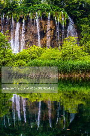 Waterfalls and lush vegetation reflected in a lake at the Plitvice Lakes National Park, Croatia