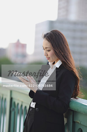 Young Japanese businesswoman with tablet by a river downtown Tokyo