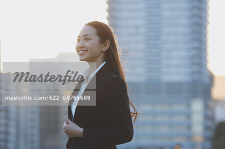 Portrait of young Japanese businesswoman by a river downtown Tokyo
