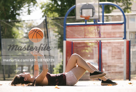 Young woman lying on basketball court throwing ball