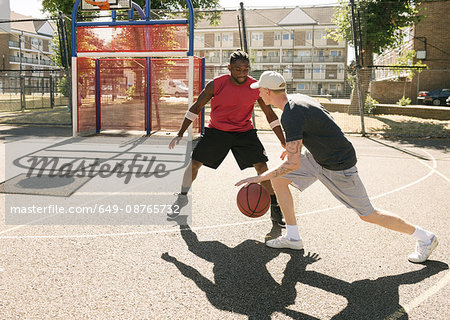 Two male basketball players practising on basketball court