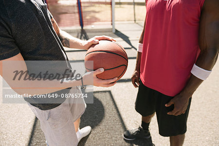 Mid section of two male basketball players with ball on basketball court