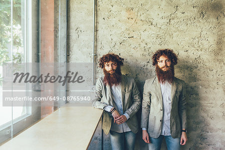 Portrait of identical male hipster twins in office