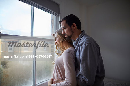 Mid adult couple gazing out through bedroom window